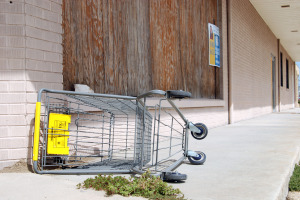 Empty Cart in front of a boarded up Dollar General store