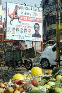 A political poster behind a stand of fresh fruit